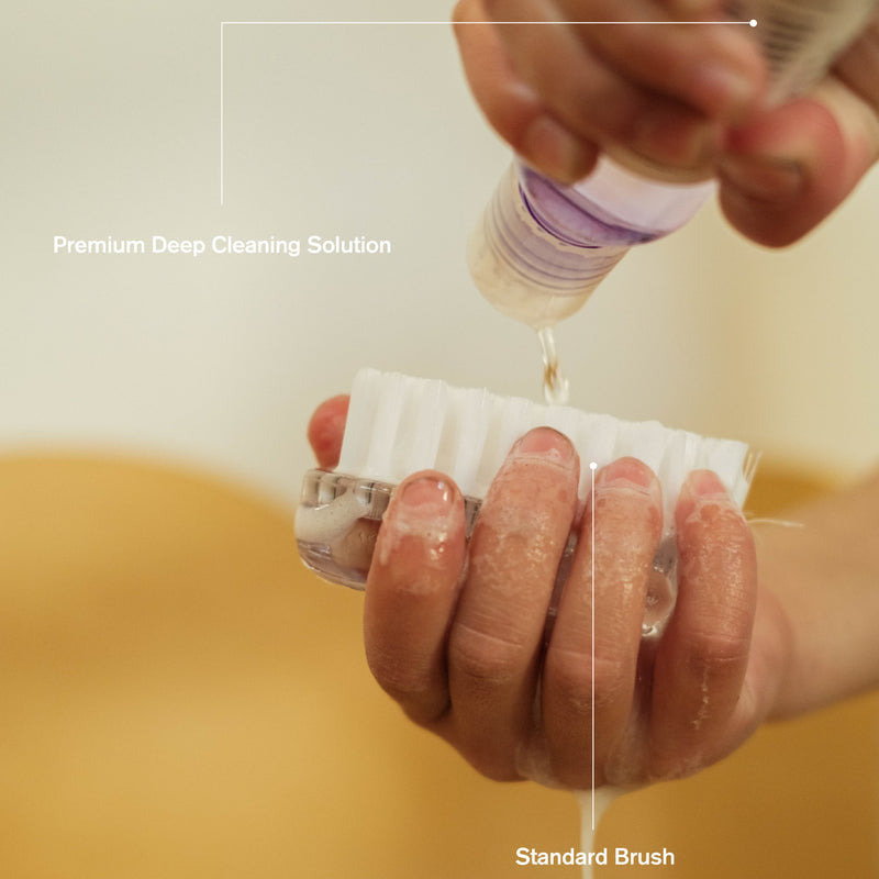 Cleaner bottle dripping onto a bristled brush for deep shoe cleaning