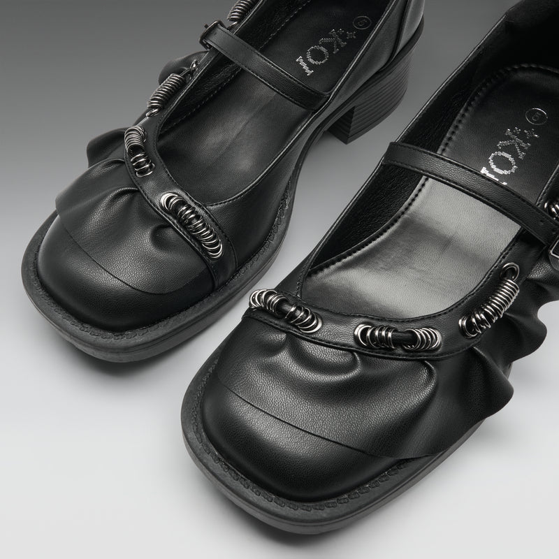 A pair of black Mary Jane-style shoes with textured spiral embellishments on the straps, shown on a neutral gray background. The brand name 'IOKZO' is visible on the insole.