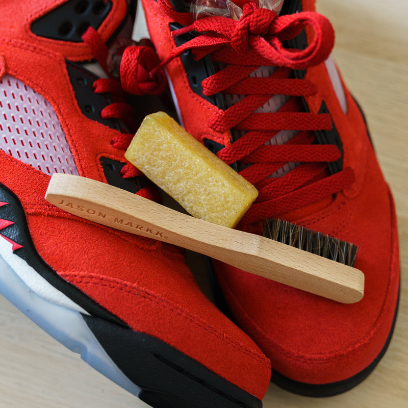 Suede shoe with wooden brush and yellow suede eraser on red upper