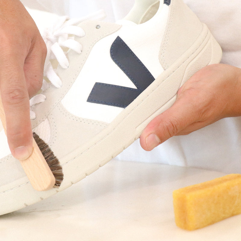 White suede sneaker detail cleaned with wooden brush and yellow eraser