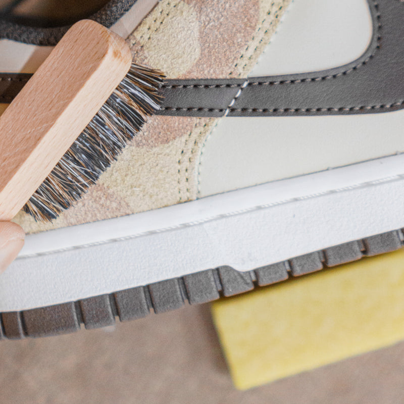 Suede shoe brushed near sole with wooden brush and yellow eraser block