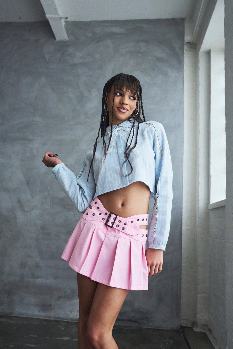Woman wearing a light blue shirt and pink skirt in an indoor setting
