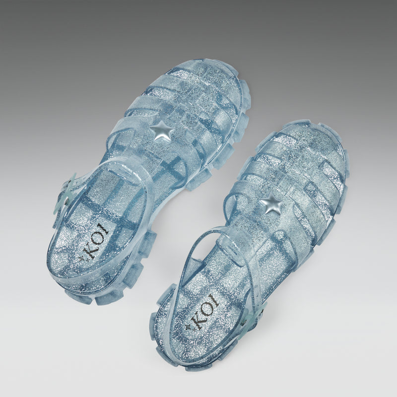 Pair of blue jelly sandals with star design on a gray background