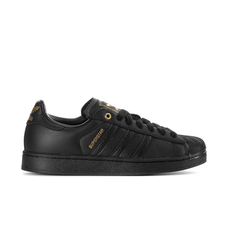 Men's black leather sneakers with gold Superstar stripe accents and lace-up design.