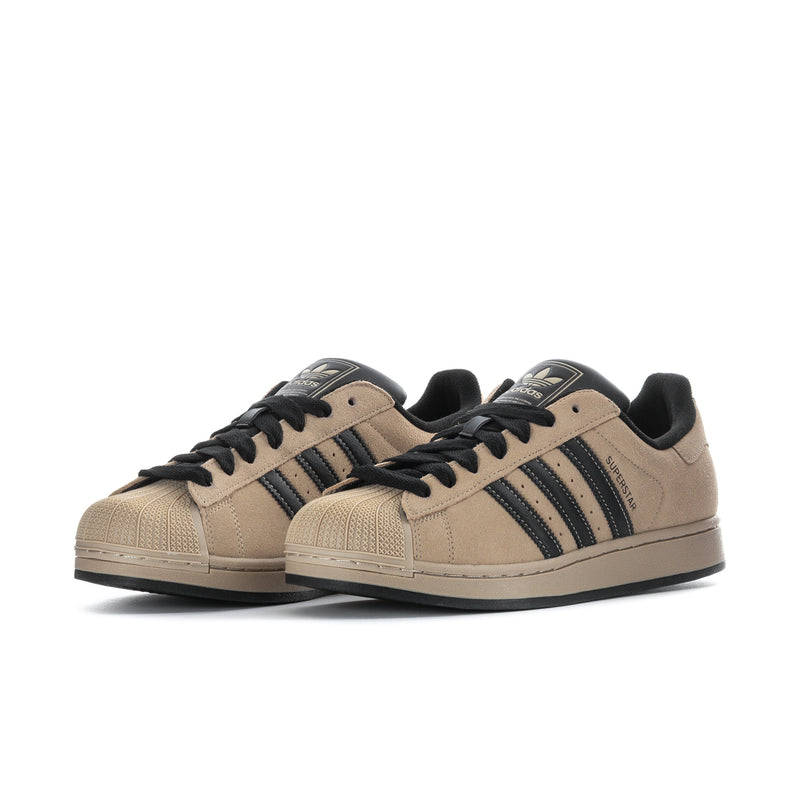 Pair of tan lace-up sneakers with black laces and navy three-stripe design