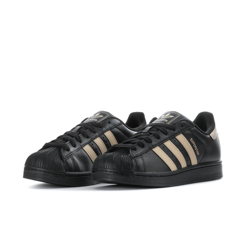 Black adidas low-top sneakers with beige triple stripes and black lace-up front.