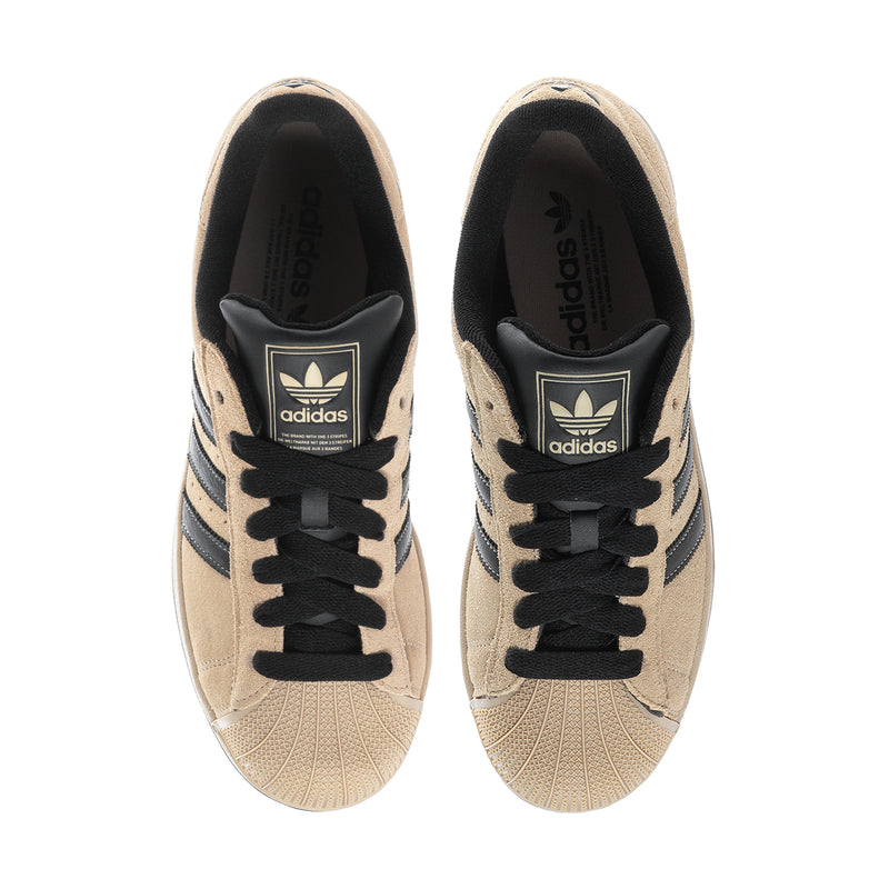 Tan sneakers with black tongue lining and adidas logo on inner collar