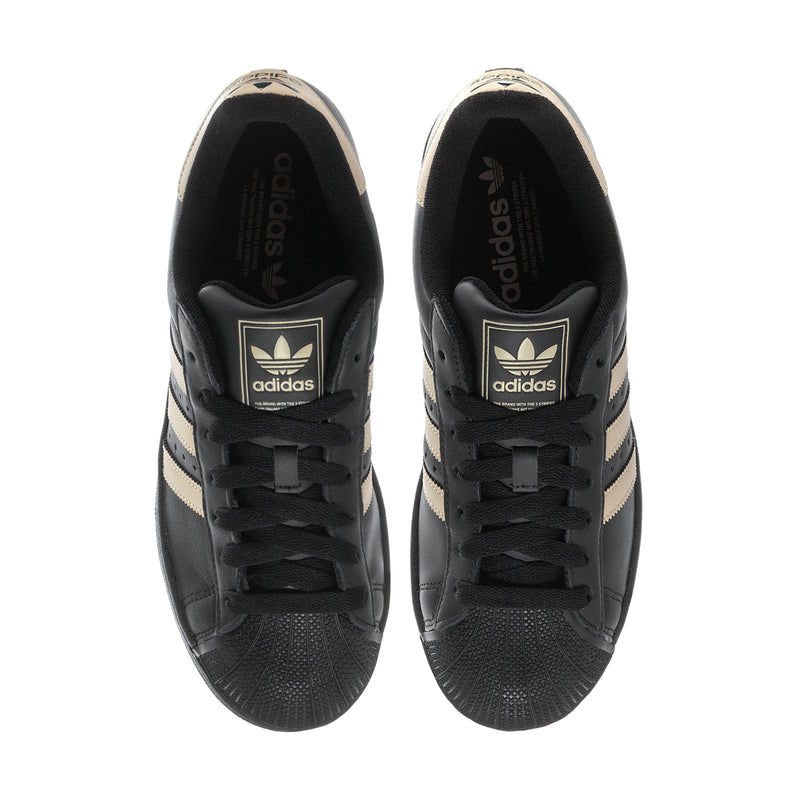 Black adidas sneakers with black insoles and lace-up tongues, beige accents at heel.