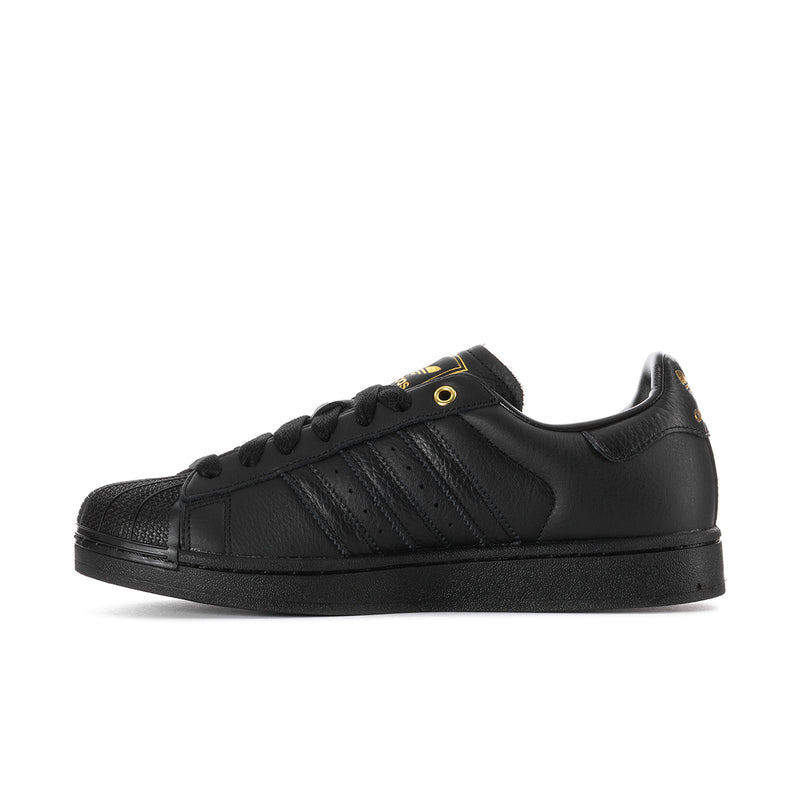 Men's black Adidas sneakers with gold-trimmed collar and three stripes near toe.