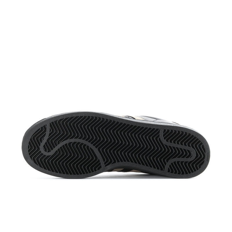 Black rubber outsole with zigzag tread pattern under adidas Superstar sneakers.