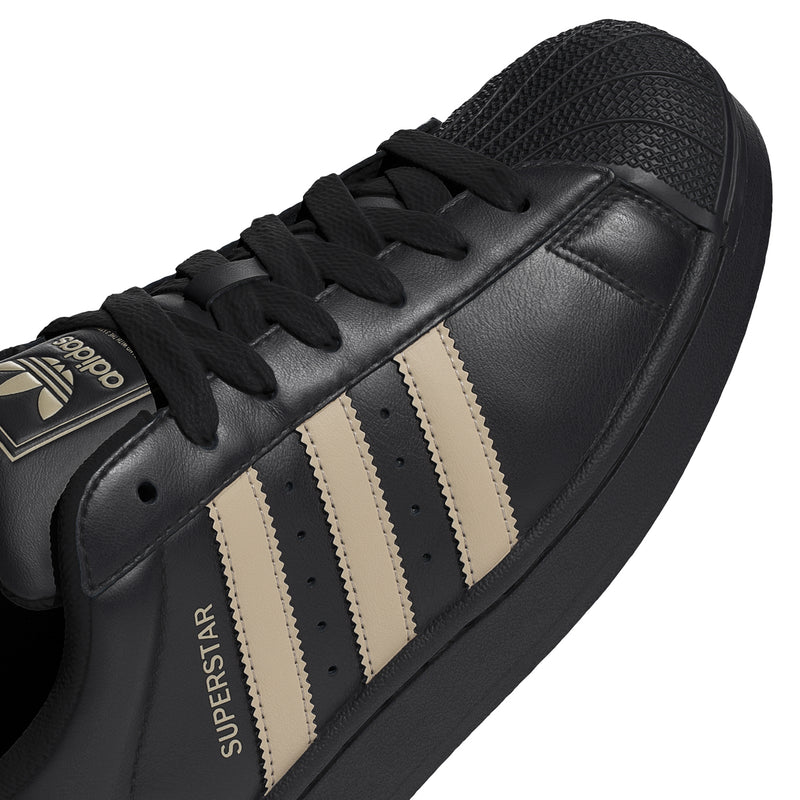 Black leather adidas sneakers upper with lace-up panel and beige triple stripes.
