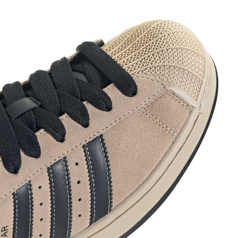 Tan suede sneaker upper with black laces and navy three-stripe details