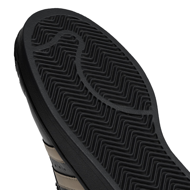 Black rubber outsole with molded zigzag tread texture, adidas Superstar sneakers.