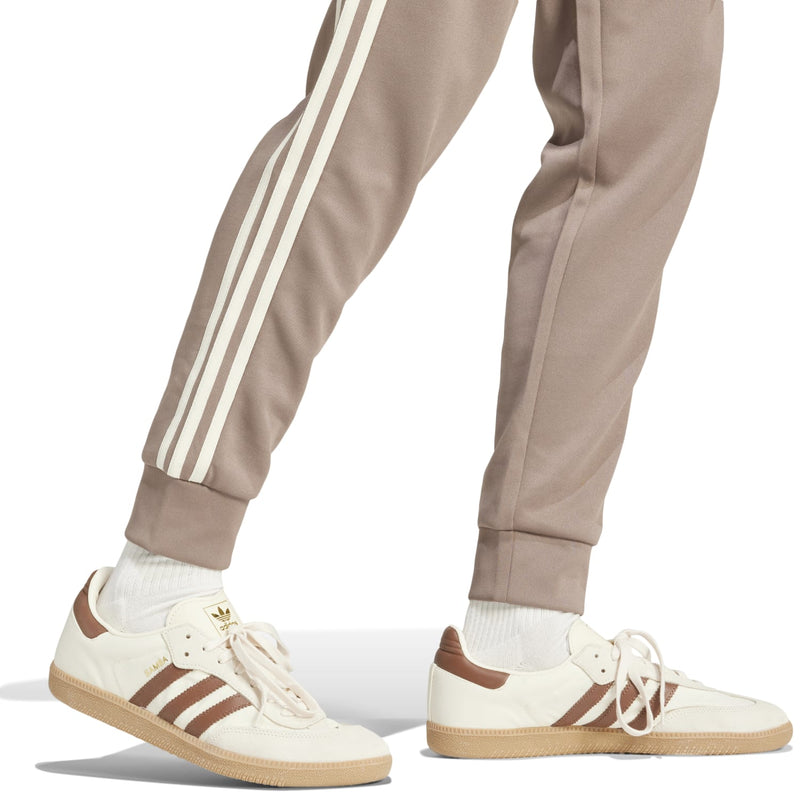Taupe track pants with white side stripes and ribbed ankle cuffs