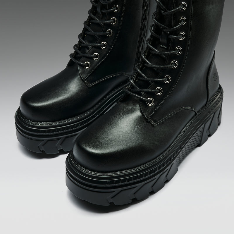 Pair of black leather boots with thick soles on a gradient background