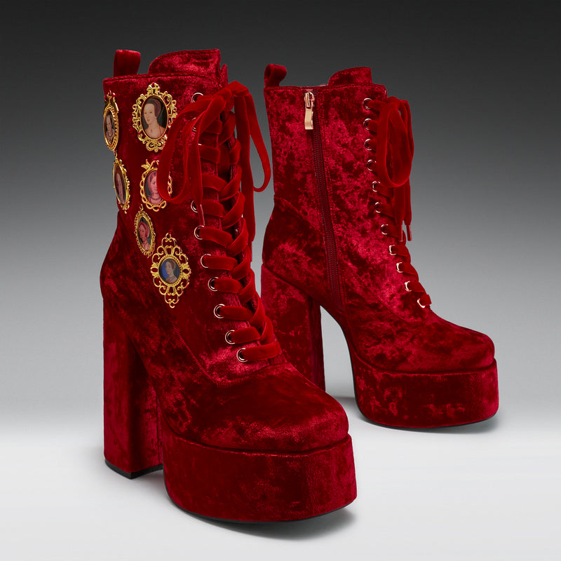 Red velvet platform boots with decorative elements on a gray background
