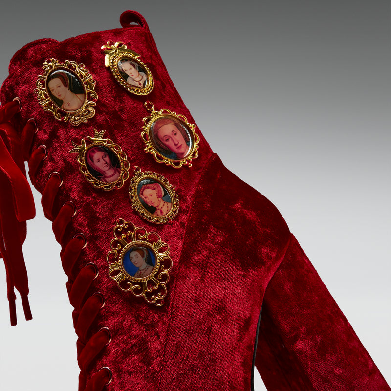 Red velvet boot with gold embellishments featuring portraits on a gray background