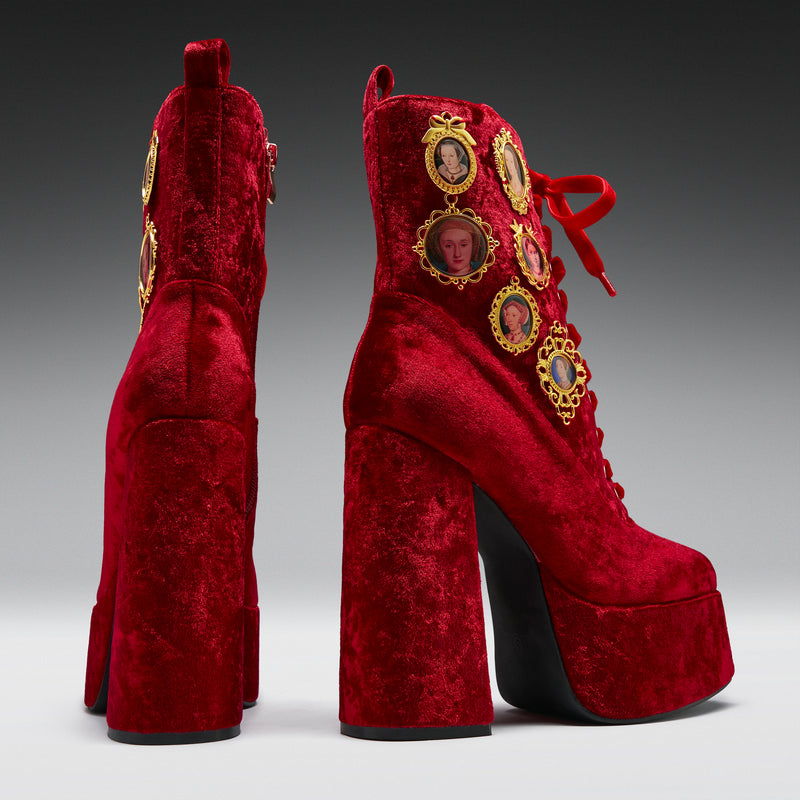 Red velvet platform boots with gold embellishments on a gray background