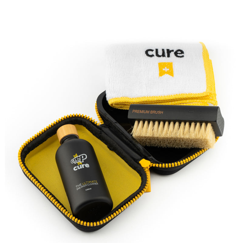 Sneaker cleaning kit open pouch with bottle, brush, and folded white microfiber cloth