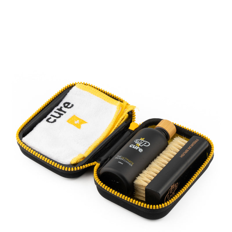 Sneaker cleaning kit in black zip case with cleaner bottle, brush, and microfiber cloth