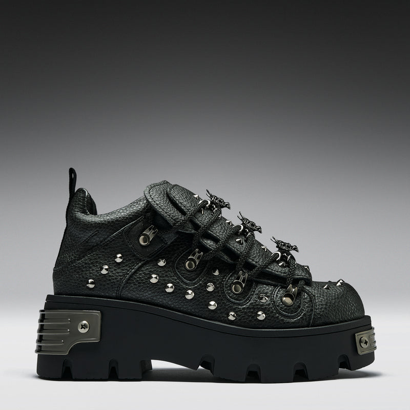 Black studded sneaker on a gray background