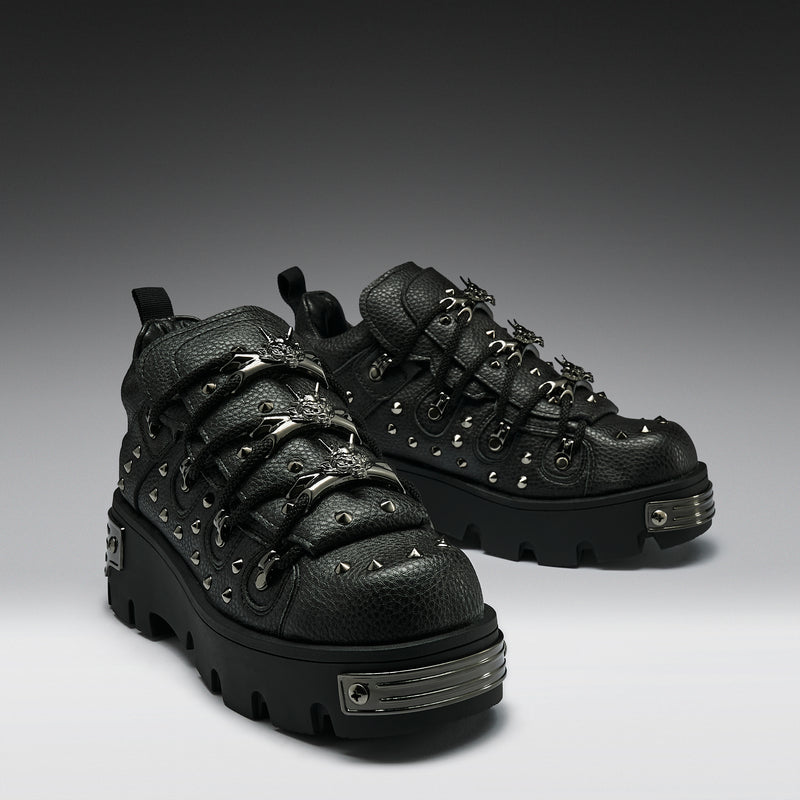 Pair of black leather boots with studs and metal accents on a gradient background