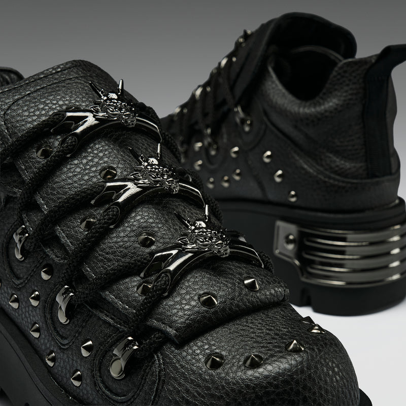 Black leather boots with metal accents on a dark background