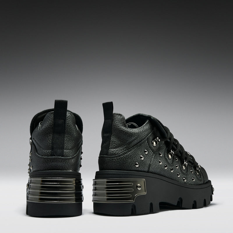 Black sneakers with textured design and thick soles on a gray background