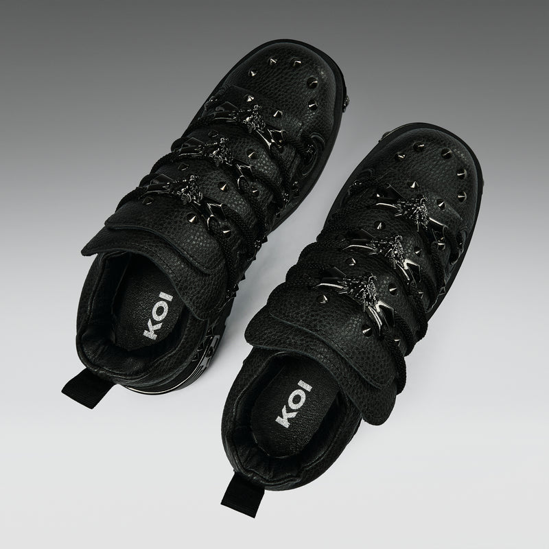 Pair of black high-top sneakers with decorative elements on a gradient background