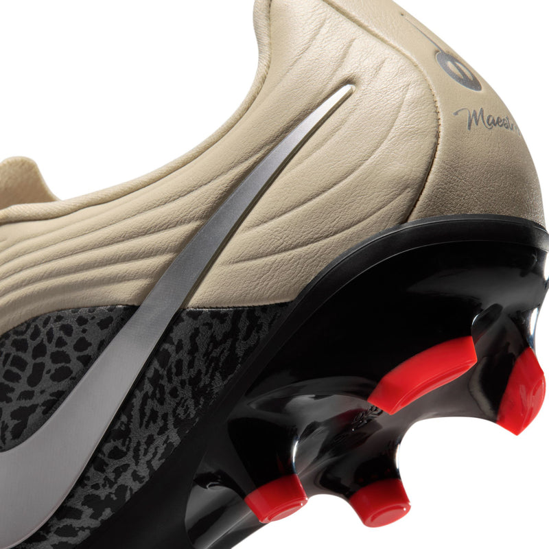 Close-up of men's soccer cleat: cream upper, black sole and red studs
