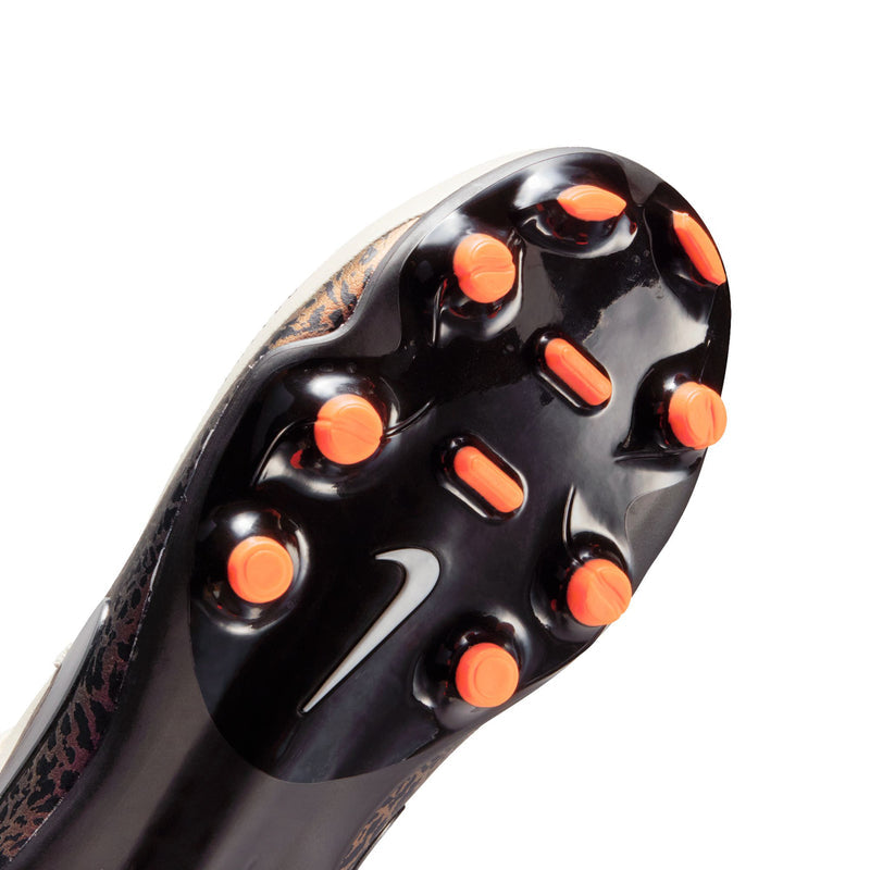 Close-up outsole view of youth soccer cleats: black studs with orange tips for traction