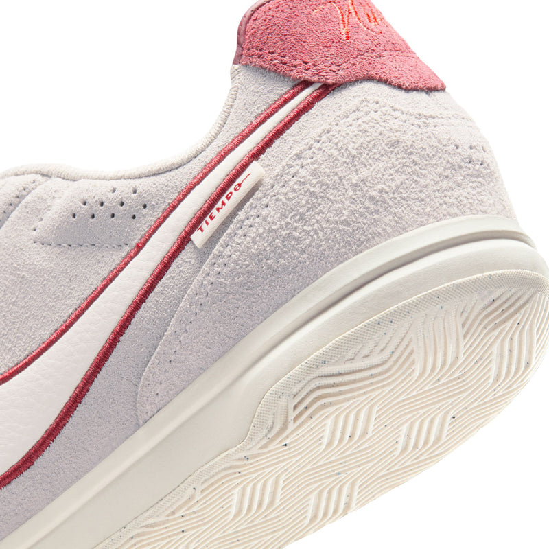 Men's sneaker side close-up, gray suede with red stripe and textured white rubber sole