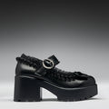 Black platform shoe with a silver buckle on a gray background