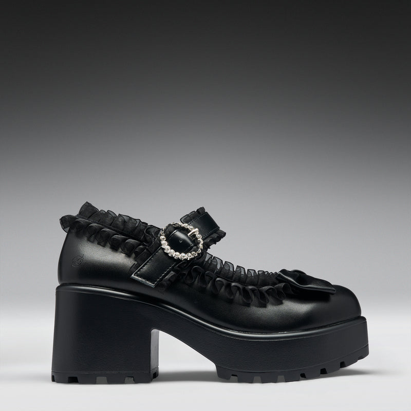 Black platform shoe with a silver buckle on a gray background