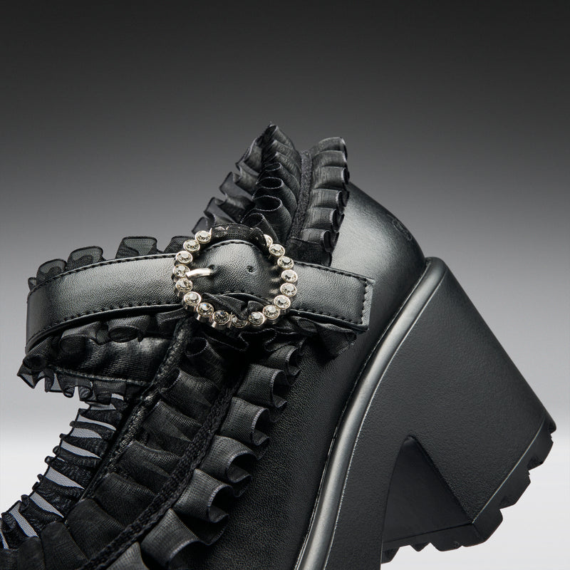 Black platform mary jane shoes with decorative elements on a gradient background