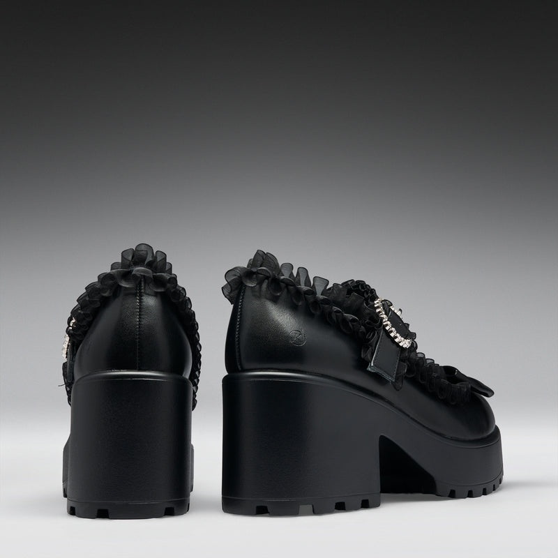 Black high-heeled shoes with decorative elements on a gray background
