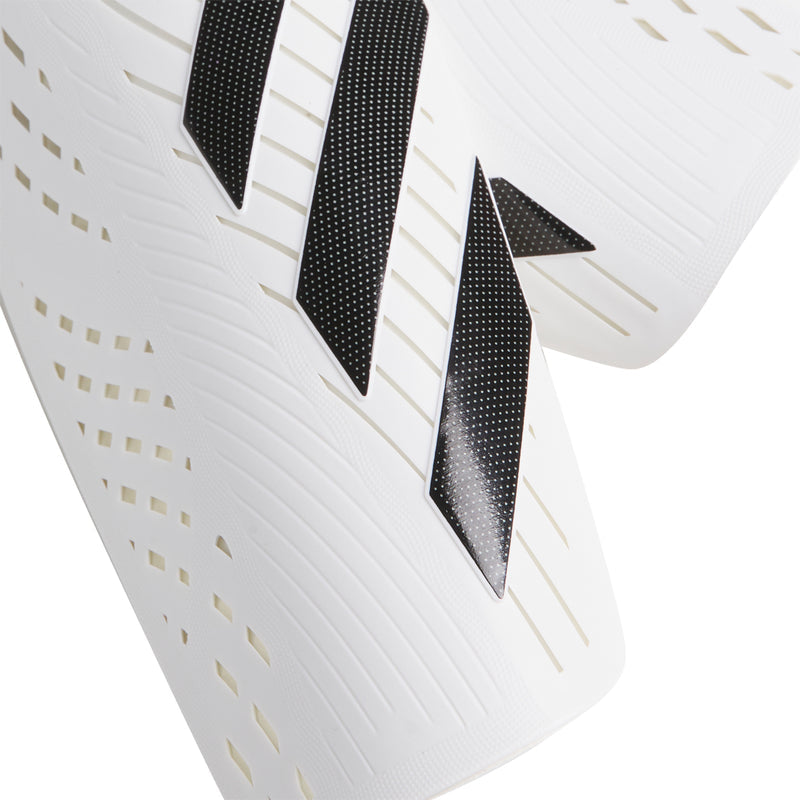 White slip-in shin guard with black chevron stripes and perforated texture, close-up
