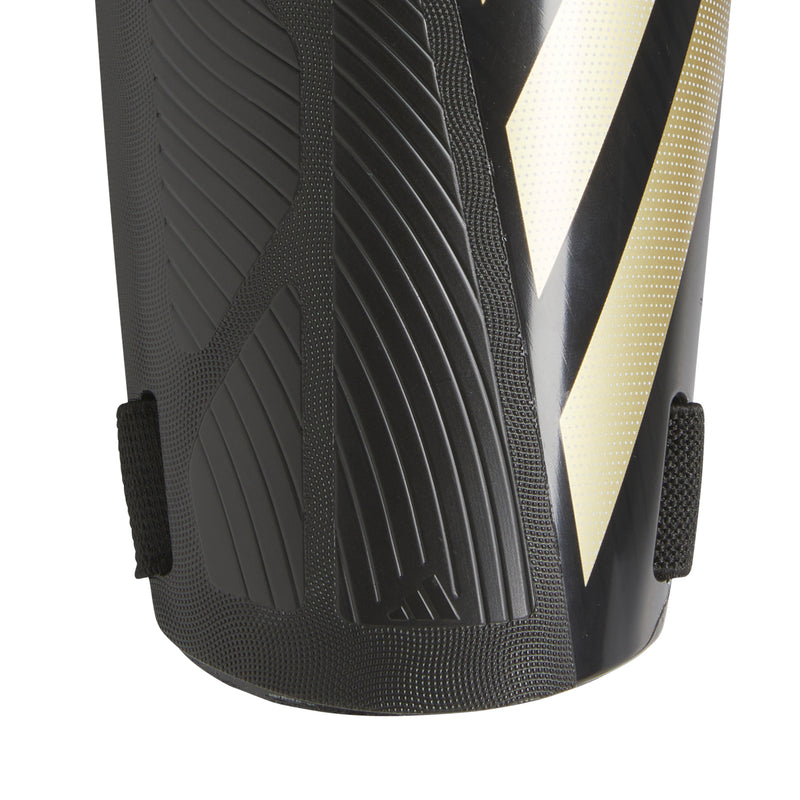 Black shin guard close-up with raised grip texture and white diagonal stripe