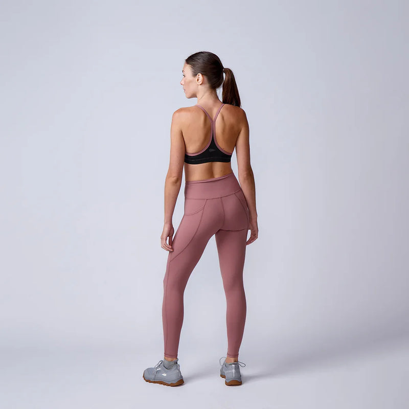 Woman in athletic wear facing away, wearing mauve leggings, sports bra, and GORUCK shoes