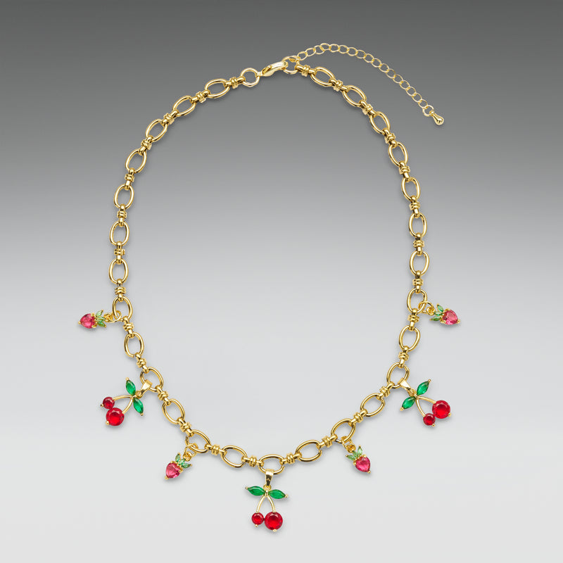 Gold necklace with red and green gemstones on a gray background