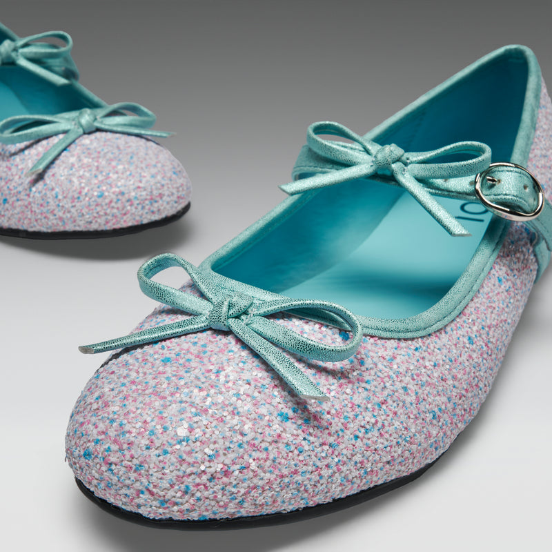 Pair of glittery shoes with bows on a light gray background