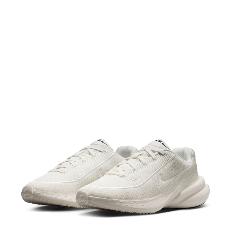 Pair of light white sneakers with lace-up closure and curved sidewalls