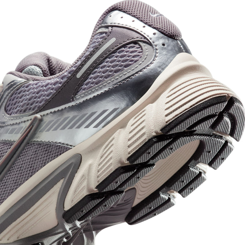 Nike running sneaker close-up, gray upper with off-white sole and black outsole tread
