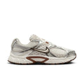 White and light-brown Nike running sneakers, side profile with swoosh and cushioned sole.