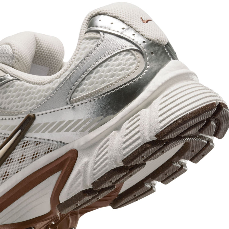 Close-up side of white Nike sneakers showing tread ridges and light-brown sole accents.