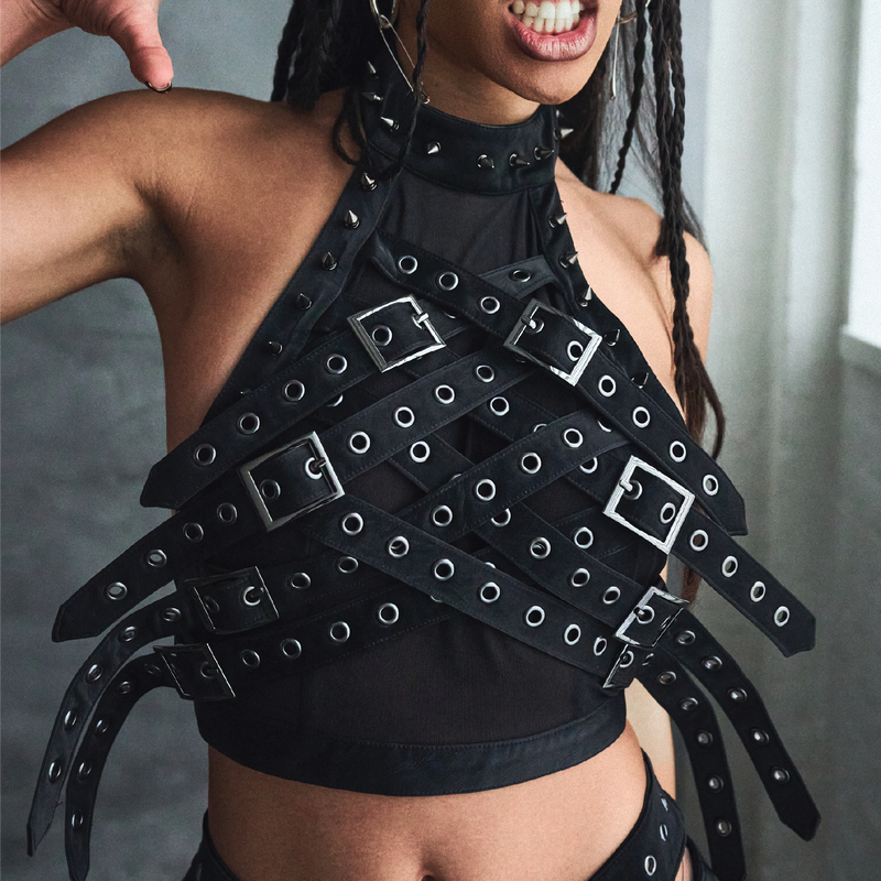 Person wearing a black studded top with a neutral background