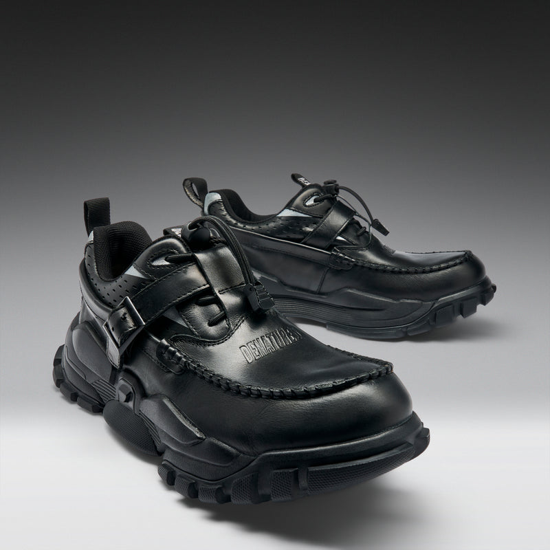 Pair of black shoes with unique design on a gradient background