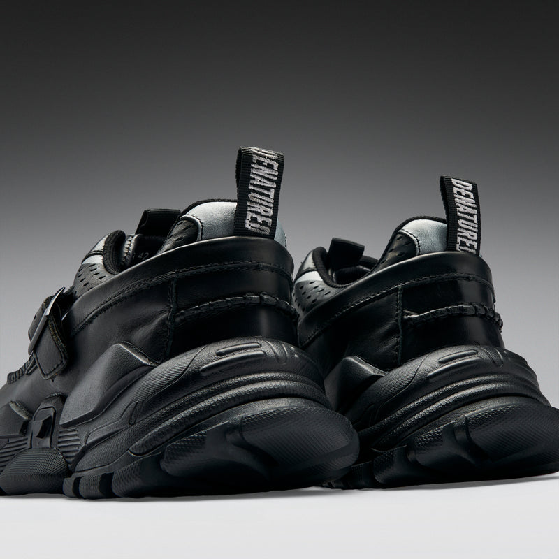 Black sneakers with 'DENATURED' print on a gradient background