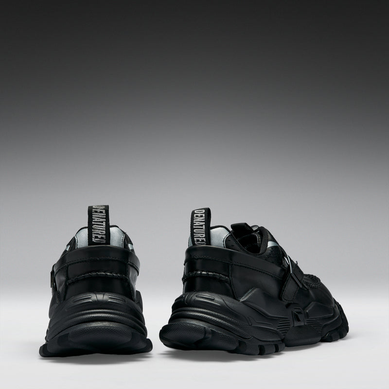 Black sneakers with visible brand logo on a gradient gray background