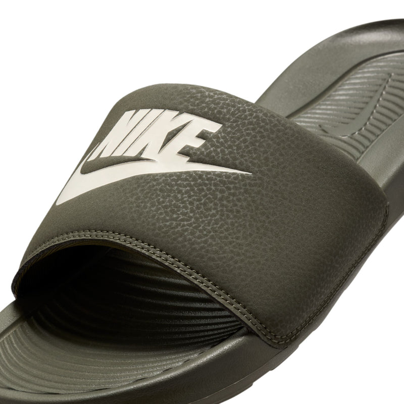 Dark olive slide sandal strap close-up with white Nike swoosh and stitching